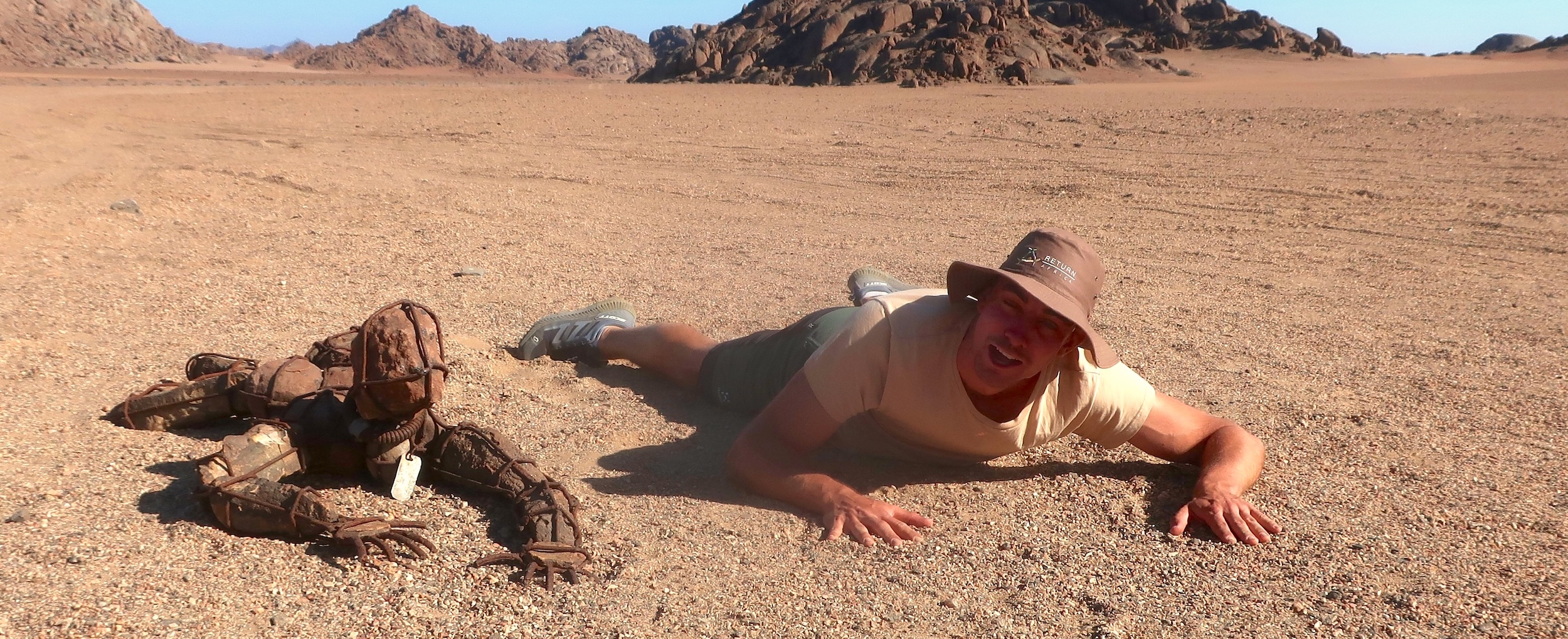 A tourist poses with one of the lone stone men of the Kunene.
