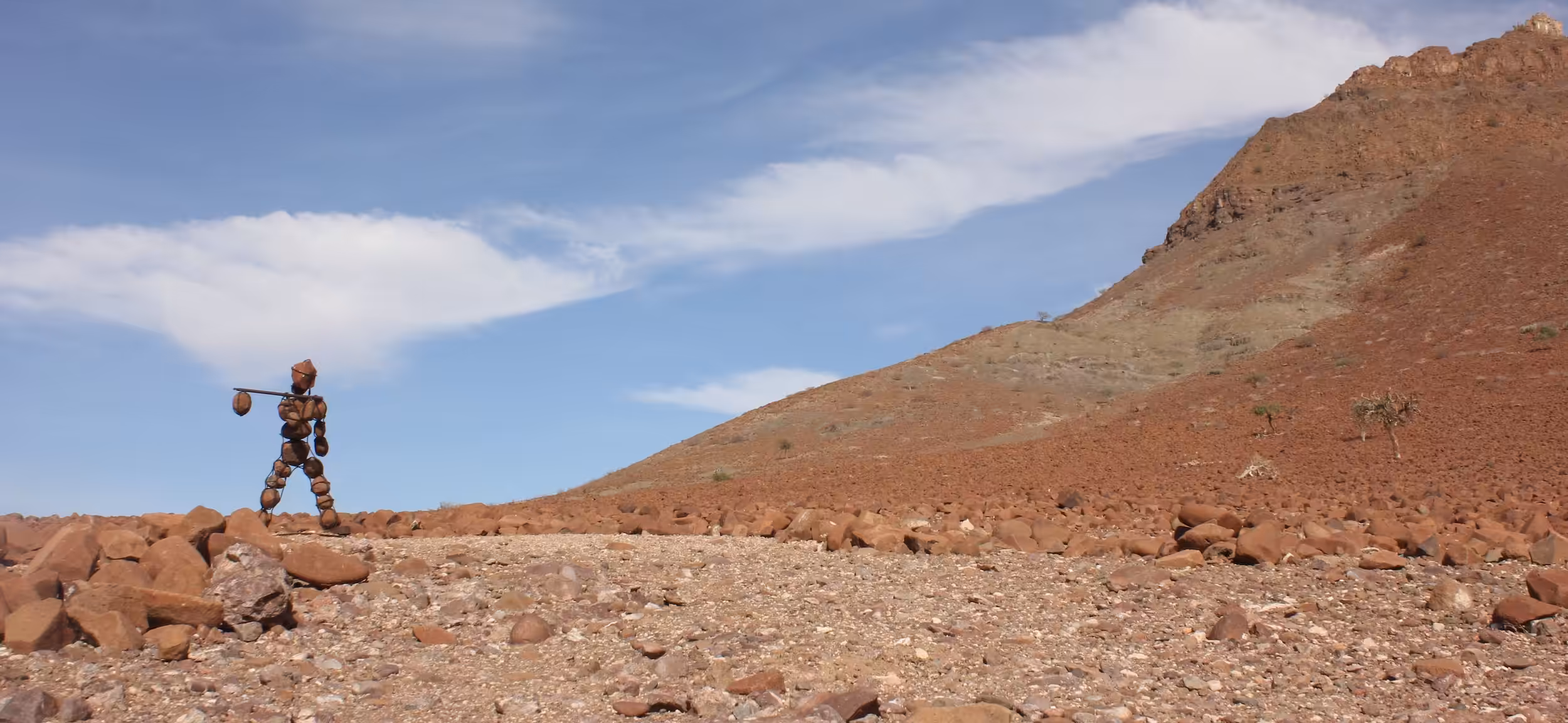 A stone figure of a man walking across a rocky plain.